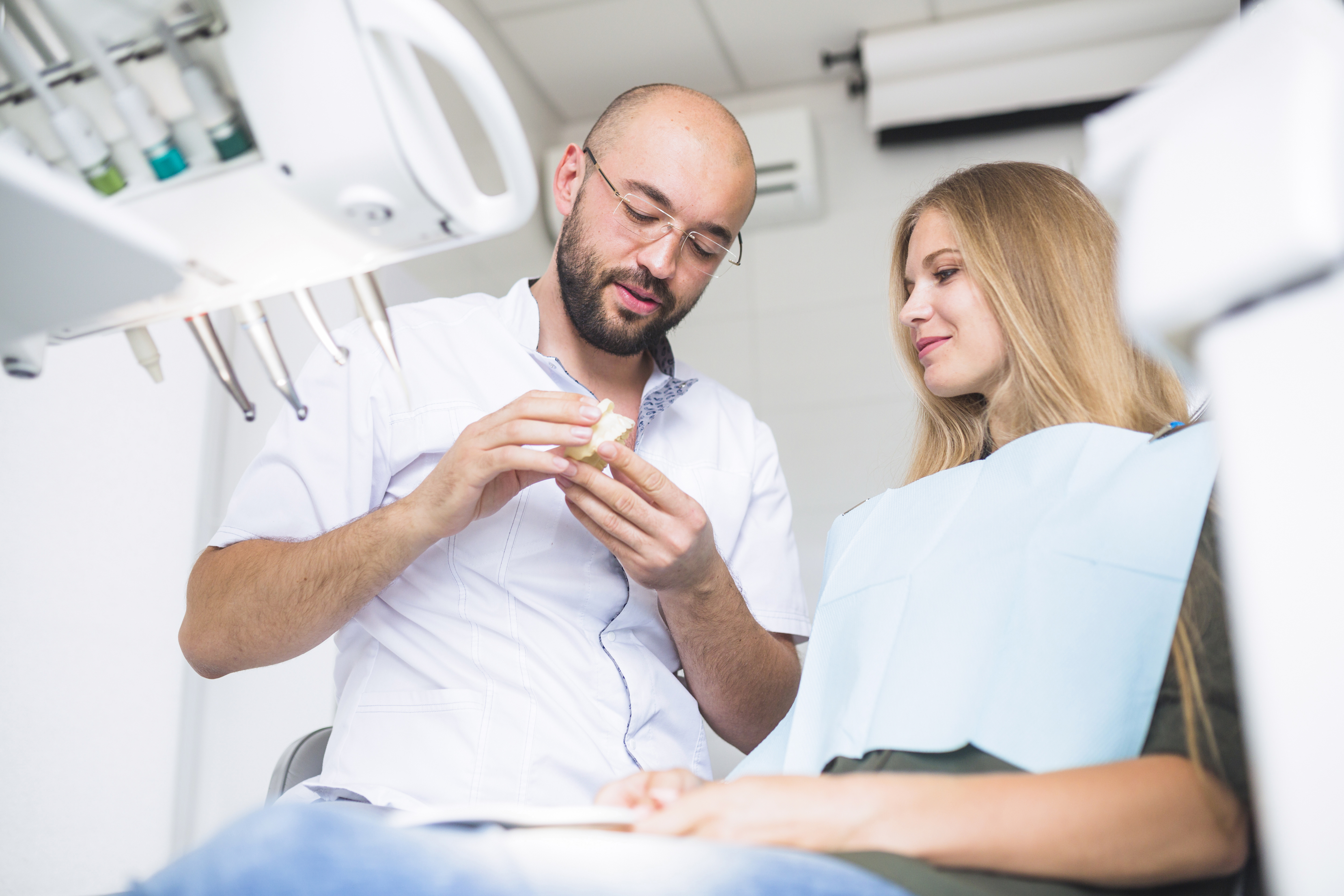 dentist holding a tooth model and discussing patient genetic history are bad teeth genetic lee simon